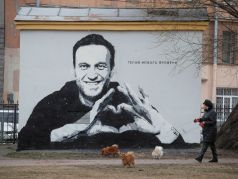 Женщина выгуливает собак перед граффити с изображением Алексея Навального в Санкт-Петербурге, Россия, 28 апреля 2021 года. Граффити гласит: 